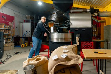 Küçük bir kızartma fabrikasında, bir işçi kızartma makinesinin yanında durmuş işlemi izliyor.