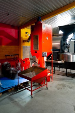 Bir kızartma fabrikasında, bir işçi hazır kahveyi poşetlere dağıtmak için bir makine kullanır.