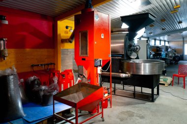 Bir kızartma fabrikasında, bir işçi hazır kahveyi poşetlere dağıtmak için bir makine kullanır.