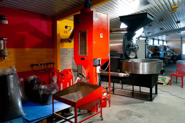 Bir kızartma fabrikasında, bir işçi hazır kahveyi poşetlere dağıtmak için bir makine kullanır.