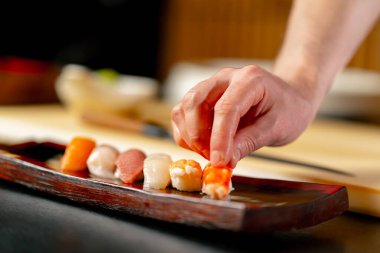 Japon restoranına yakın çekim yapan şef, tabağa çiğ balık parçaları serer.