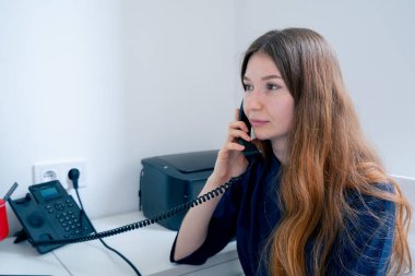 Jinekoloji muayenehanesinde mavi üniformalı bir doktor hasta için randevu alır.