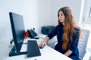 Jinekoloji muayenehanesinde mavi üniformalı bir doktor hasta için randevu alır.