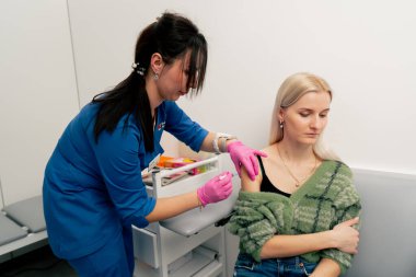 Analiz odasındaki özel bir klinikte doktor hastanın omzuna aşı yapar.