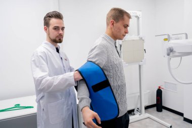 Özel bir klinikte, beyaz bir röntgen odasındaki hasta bir prosedüre hazırlanır.