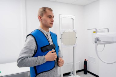 Özel bir klinikte, beyaz bir röntgen odasındaki hasta bir prosedüre hazırlanır.