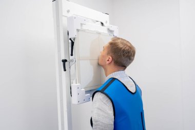 Özel bir klinikte, beyaz bir röntgen odasındaki hasta bir prosedüre hazırlanır.