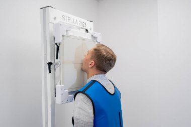 Özel bir klinikte, beyaz bir röntgen odasındaki hasta bir prosedüre hazırlanır.