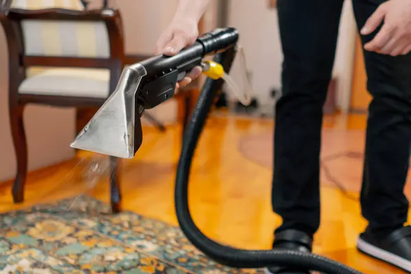 close up in the apartment master cleaner waters the carpet with detergent from a professional vacuum cleaner