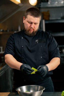 Profesyonel bir mutfakta, şef marul yapraklarını demir bir kase gibi parçalar.