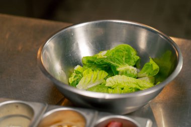 Profesyonel bir mutfakta, Yunan salatasının tüm malzemeleri demir bir masanın üzerinde.