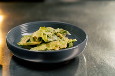 Tabakta soslu profesyonel marul parçalarının yakın plan çekimi bir tabak oluşturur.