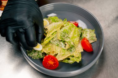 Profesyonel mutfak malzemelerine yakın plan soslu, domatesli ve aşçı tabağa yumurta koydu.