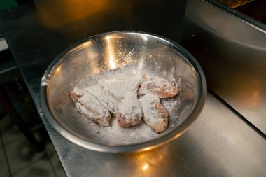 Profesyonel bir mutfakta, un serpiştirilmiş tavuk kanadı serpiştirilmiş.