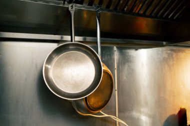 Profesyonel bir mutfakta yakın plan yemek pişirmek için duvar tutacağında iki tava var.