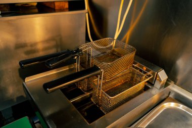 Profesyonel bir mutfakta yakın plan bir çift kızartma makinesi ve patates kızartması seti var.