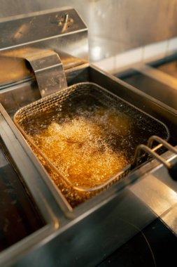 Profesyonel bir mutfakta yakın plan çekimde tavuk kanatlarını fritözde kızartıyorum.