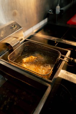 Profesyonel bir mutfakta tavuk kanatlarının kızartıldığı yakın çekim.