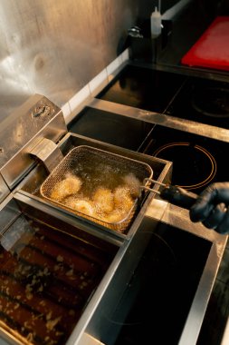 Profesyonel bir mutfakta tavuk kanatlarının kızartıldığı yakın çekim.