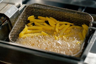Profesyonel bir mutfakta yakın plan çekimde kızartma kızartmasını fritözde yağda kızartıyorum.
