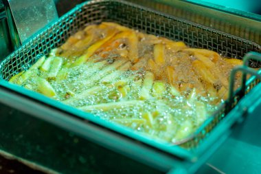 Profesyonel bir mutfakta yakın plan, yağda patates kızartması kızartıyorlar.