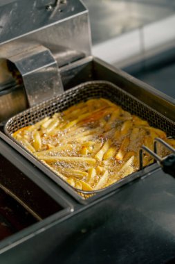 Profesyonel bir mutfakta yakın plan çekimde kızartma kızartmasını fritözde yağda kızartıyorum.