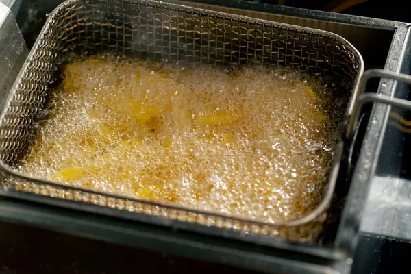 close-up in a professional kitchen frying French fries in oil in a deep fryer