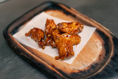 Profesyonel mutfakta, ahşap tepside hazır tavuk kanadı.