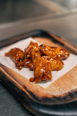 Profesyonel mutfakta, ahşap tepside hazır tavuk kanadı.