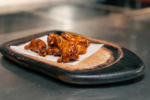 close-up in professional kitchen ready-made chicken wings on a wooden tray
