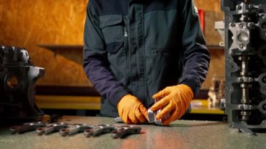 Masadaki bir benzin istasyonunda genç bir motor tamircisi yeni bir piston parçası monte ediyor.