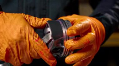 Masadaki bir benzin istasyonunda genç bir motor tamircisi yeni bir piston parçası monte ediyor.
