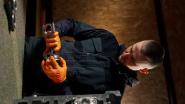 bir servis istasyonunda genç bir motor tamircisi yeni bir piston parçası monte eder
