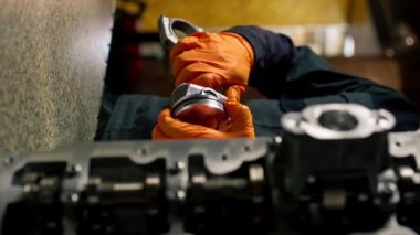 bir servis istasyonunda genç bir motor tamircisi yeni bir piston parçası monte eder