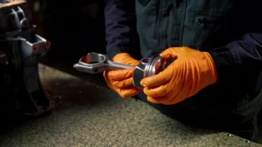 Masadaki bir benzin istasyonunda genç bir motor tamircisi yeni bir piston parçası monte ediyor.