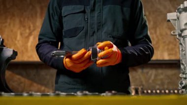 Masadaki bir benzin istasyonunda genç bir motor tamircisi yeni bir piston parçası monte ediyor.