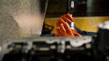 bir servis istasyonunda genç bir motor tamircisi yeni bir piston parçası monte eder