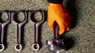 Bir benzin istasyonuna yakın çekim yapan usta, masanın üzerinde yatan piston parçalarından birini alır.