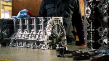 Bir benzin istasyonunda tamirci mavi bir peçeteyle motordan yağ siler.