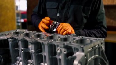 Masanın üstündeki bir benzin istasyonunda genç bir tamirci piston parçası yerleştiriyor.