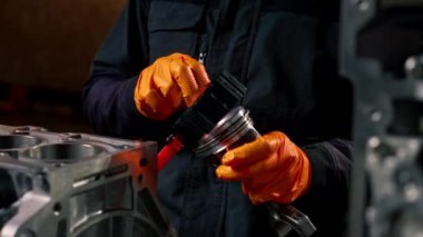 Masanın üstündeki bir benzin istasyonunda genç bir tamirci piston parçası yerleştiriyor.