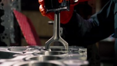 Masanın üstündeki bir benzin istasyonunda genç bir tamirci piston parçası yerleştiriyor.