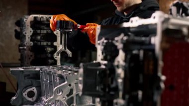 Masadaki bir benzin istasyonunda genç bir tamirci piston parçası yerleştiriyor.