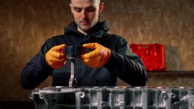 Masadaki bir benzin istasyonunda genç bir tamirci piston parçası yerleştiriyor.