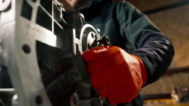 Masanın üstündeki bir benzin istasyonunda genç bir motor tamircisi manuel olarak motordaki krank milini çalıştırır.