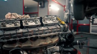 Yedek parçaların yerine konan motoru tamir eden bir arabanın motor bölümünün kapatıldığı bir benzin istasyonunda.