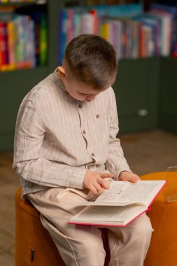 Çocuk mahallesindeki bir kitapçıda hafif giysili yakışıklı bir çocuk kitap okuyor.