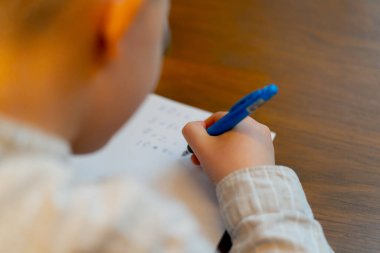 Kitapçıda yakın plan. Masada oturan yakışıklı bir çocuk matematik denklemlerini çözüyor.