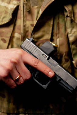 Profesyonel bir atış poligonuna yakın mesafeden bir asker cephane içinde duruyor ve elinde bir tabanca tutuyor.