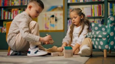 Çocukların olduğu bölgedeki bir kitapçıda uzun saçlı güzel bir kız ve oğlan tahta oyuncaklarla oynuyorlar.